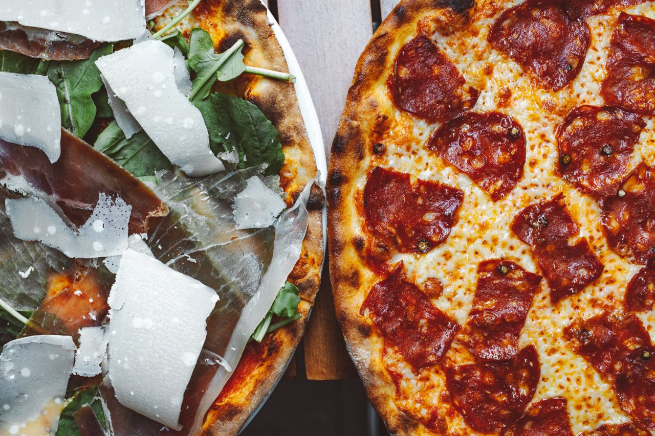 core-values Two gourmet pizzas with mouth-watering toppings including pepperoni and prosciutto, perfect for food photography.