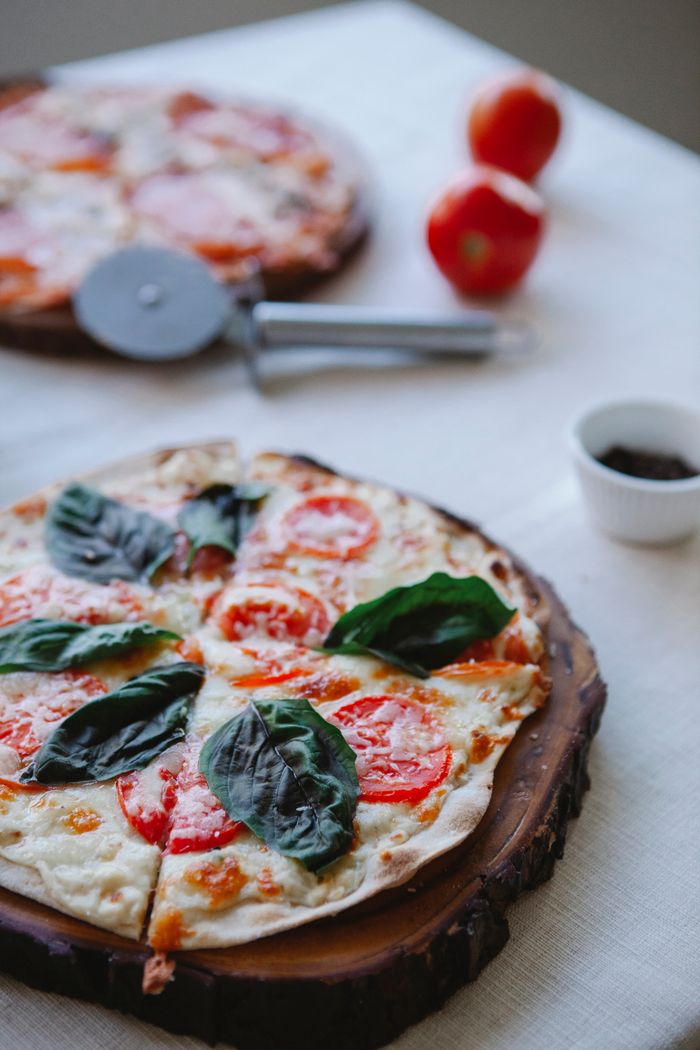 Delicious fresh basil and tomato pizza on a rustic wooden board, ready to serve.